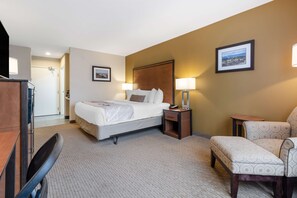 A hotel room with a bed, bedside tables, a chair, and a desk.