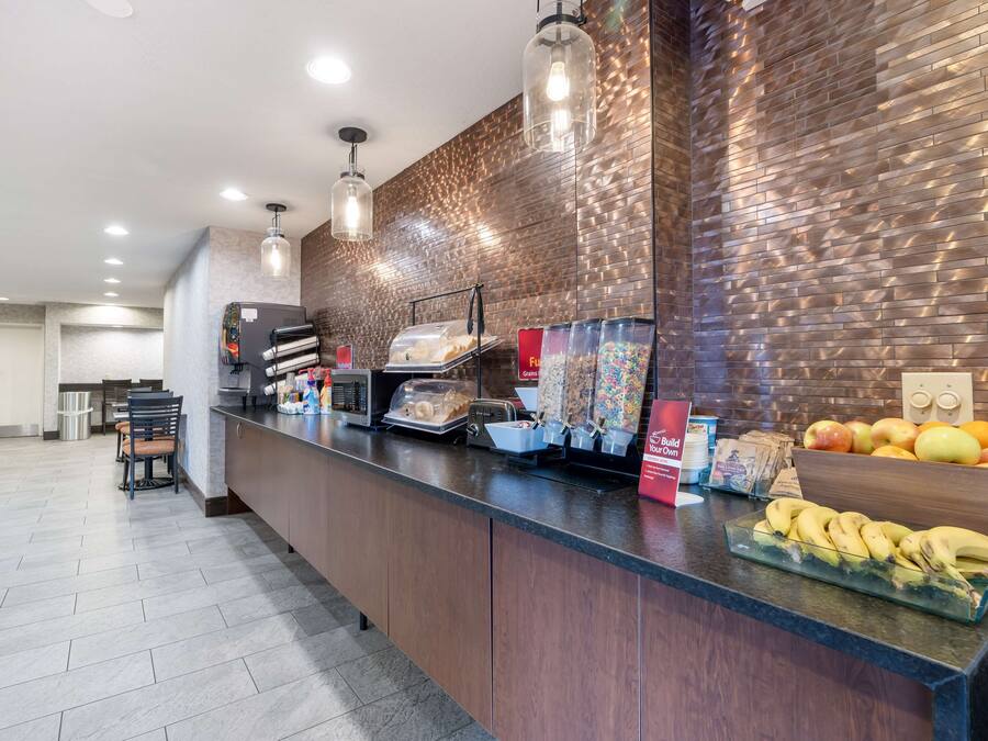 Un espace cuisine moderne avec un long comptoir, divers produits alimentaires et un mur en briques.