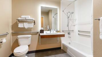 A bathroom with a toilet, sink, and bathtub. There are handrails and a mirror above the sink.