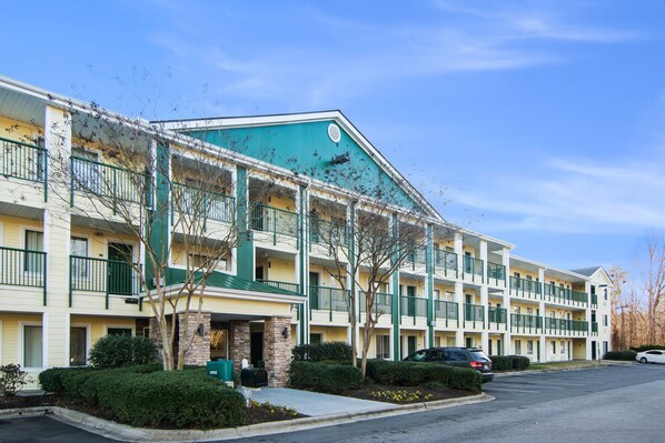 Hotel features a flat roof and balconies on each floor, offering parking and a well-manicured outdoor space.
