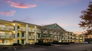 A multi-story motel with balconies and a parking lot. - Suburban Studios Durham-Raleigh (Durham)