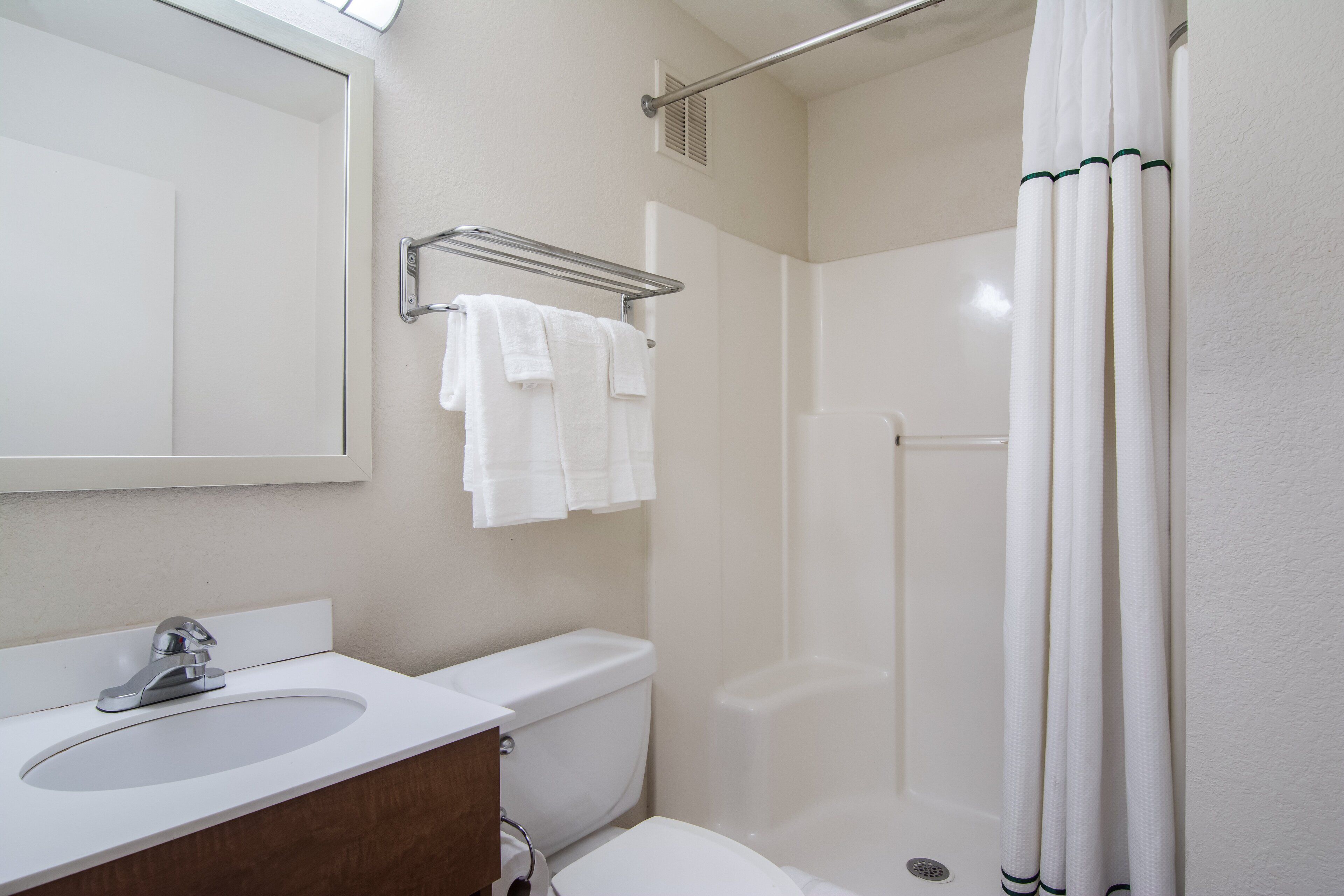 Un baño con lavabo, espejo, inodoro y cortina de ducha.
