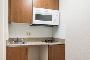 Kitchen features a microwave, stainless steel sink, and gas stove with control panel.