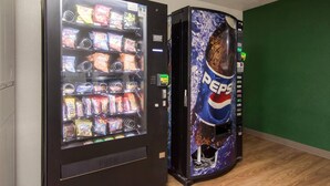 Two vending machines, one with snacks and the other with Pepsi, in a room with green walls and wooden flooring. - Suburban Studios Durham-Raleigh (Durham)