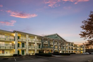 Stylish motel with a central entrance and two wings, each floor featuring a balcony with a railing.
