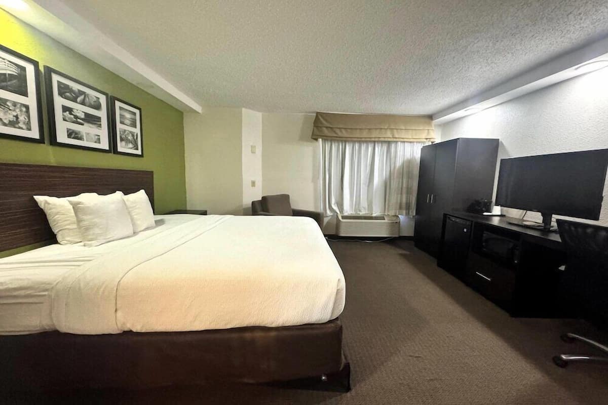 A hotel room with a bed, a desk with a computer, a television, and a chair.