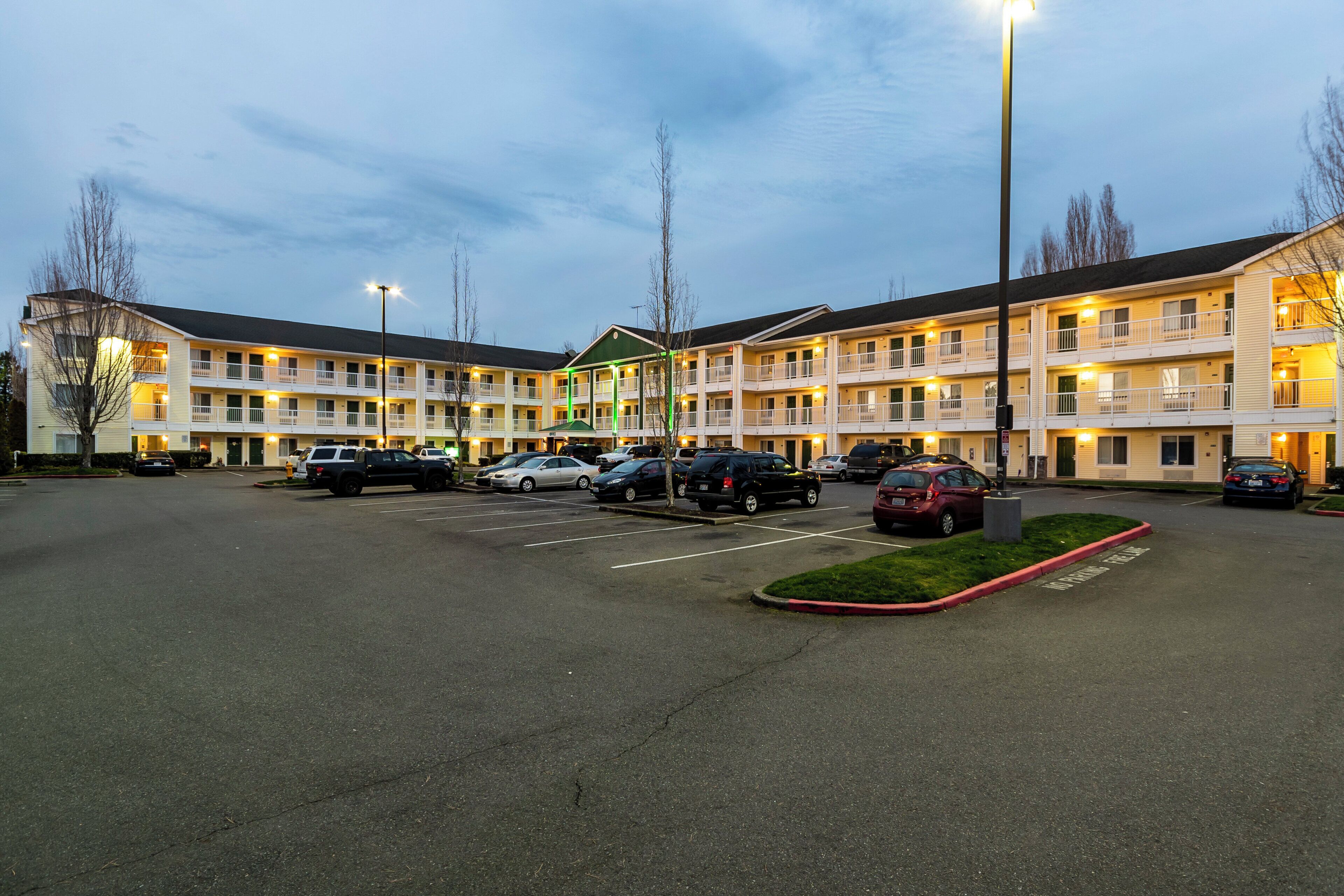 A multi-story motel with a parking lot in front.