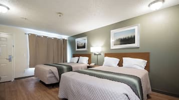 A hotel room with two beds, a bathroom, and a door.