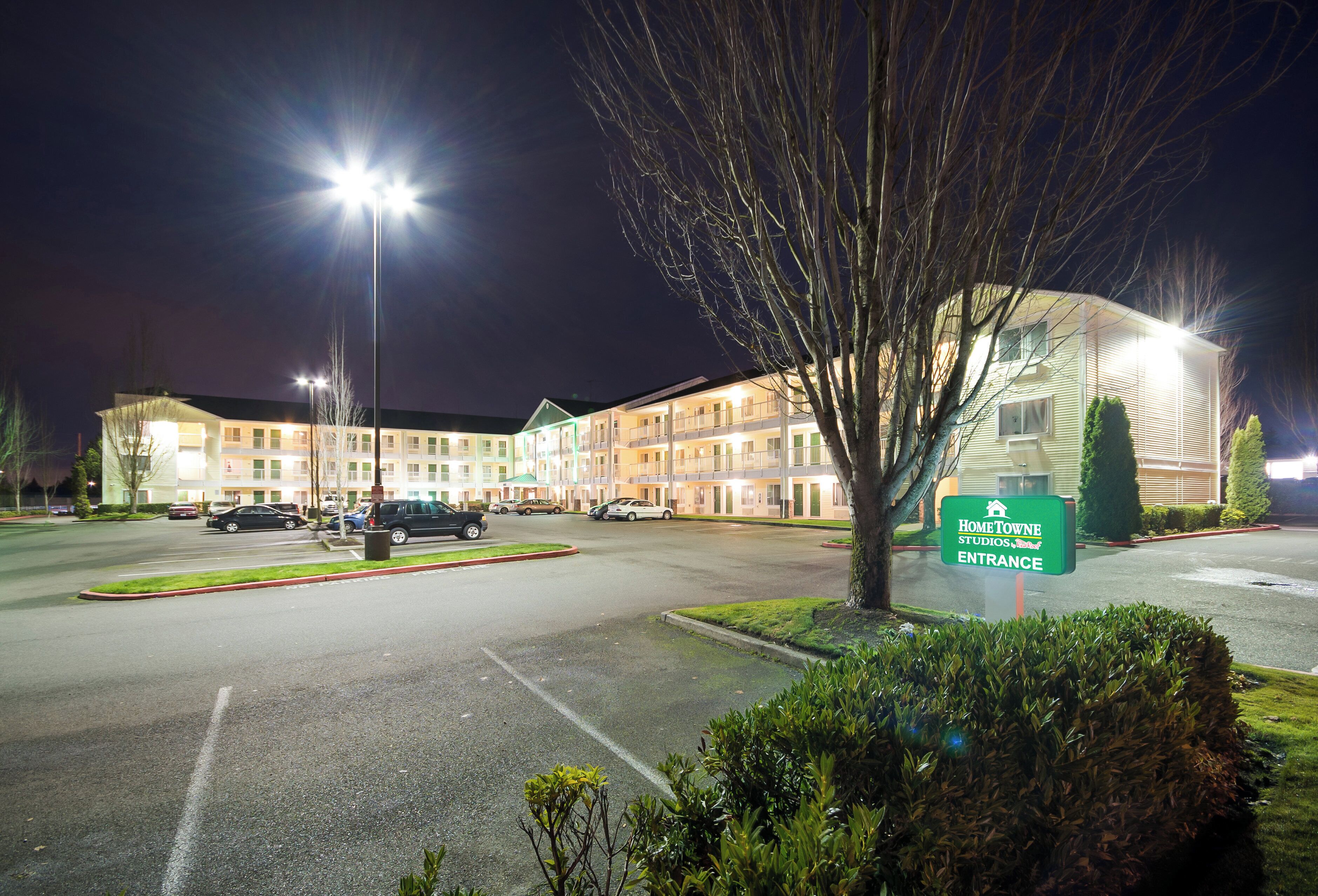 Un hôtel à plusieurs étages, doté d’une entrée bien éclairée et d’une enseigne indiquant « Home Towne Studios Suites ».