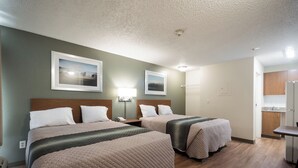 Habitación de hotel con dos camas, una kitchenette pequeña y un baño.