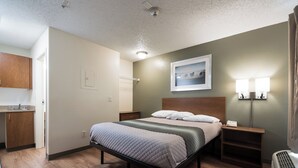 Habitación de hotel con cama, mesitas de noche, lámpara de pared, un cuadro y un radiador.