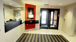 Un vestíbulo de hotel con una recepción, una señal de salida, un banco y una alfombra a rayas.