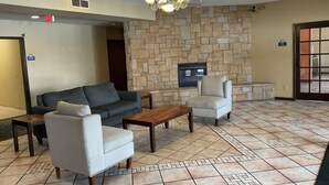 A lobby with a stone wall, a fireplace, a sofa, a chair, and a coffee table. - Days Inn by Wyndham Colorado Springs Airport (Colorado Springs)