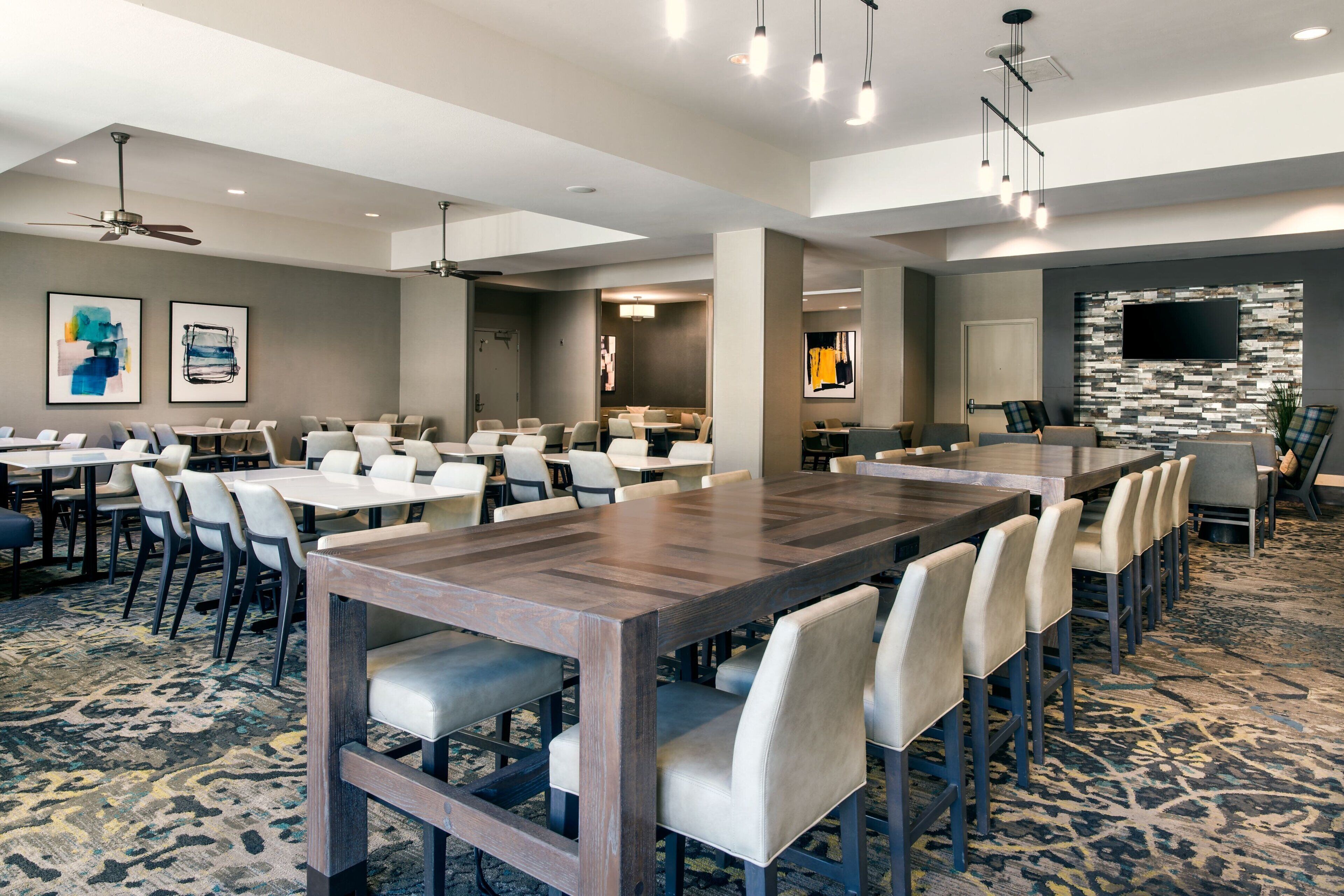 A conference room with a large wooden table, multiple chairs, and a patterned carpet.