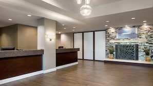 A reception area with a wooden reception desk, a stone accent wall, and a modern chandelier.