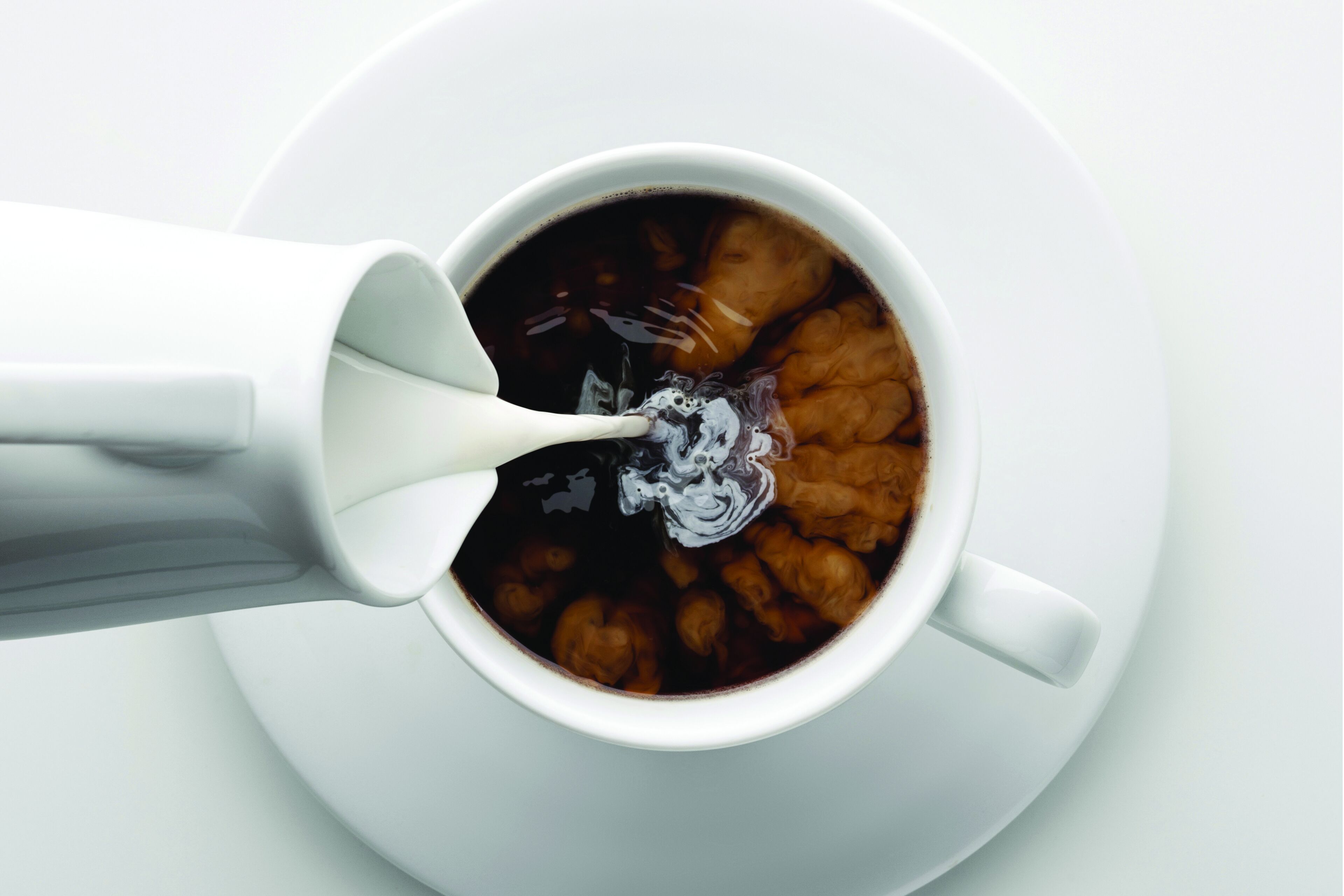 Uma chávena de café branco com uma colher.