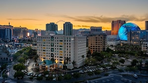 A hotel with a modern design, featuring a prominent curved entrance, surrounded by a well-maintained urban environment with clear roads and parked cars.