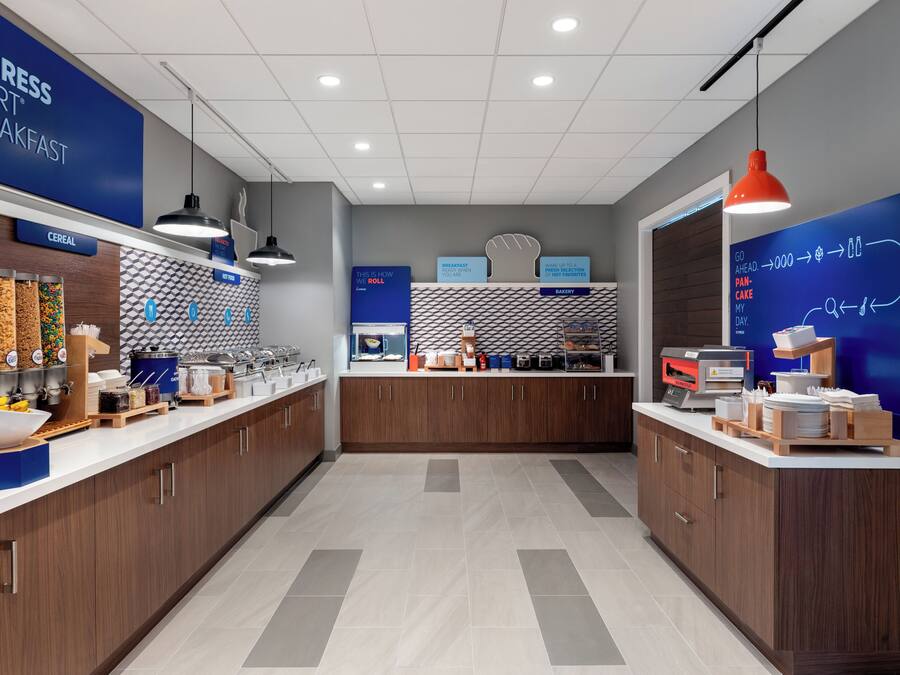 A modern breakfast area with a counter displaying various food items and a sign indicating the breakfast menu.