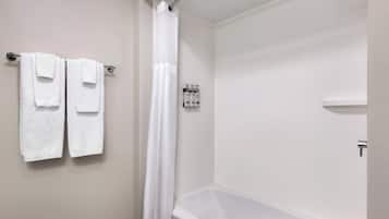 Un baño con bañera, cortina de ducha y dos toallas colgadas en un perchero.