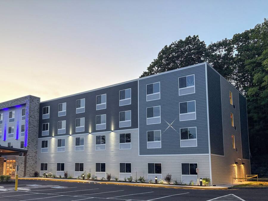 Hotel de vários andares com design moderno, combinando tijolo e revestimento metálico, e entrada destacada com área coberta.