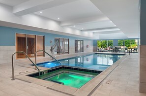 Una piscina interna con acqua cristallina, pavimento piastrellato e parete blu.