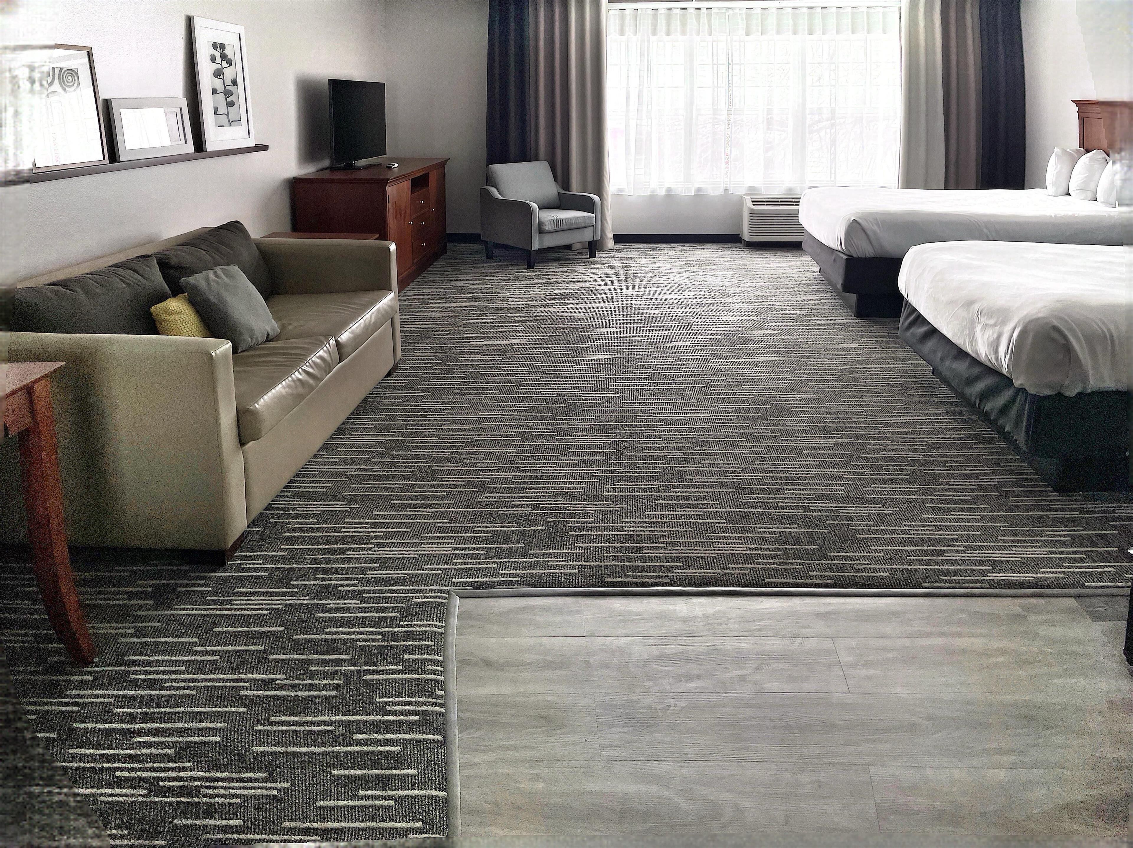 A hotel room with a sofa, a bed, a TV, and a chair.