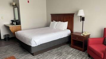 Una habitación de hotel con una cama, un escritorio con lámpara, una silla y un teléfono.