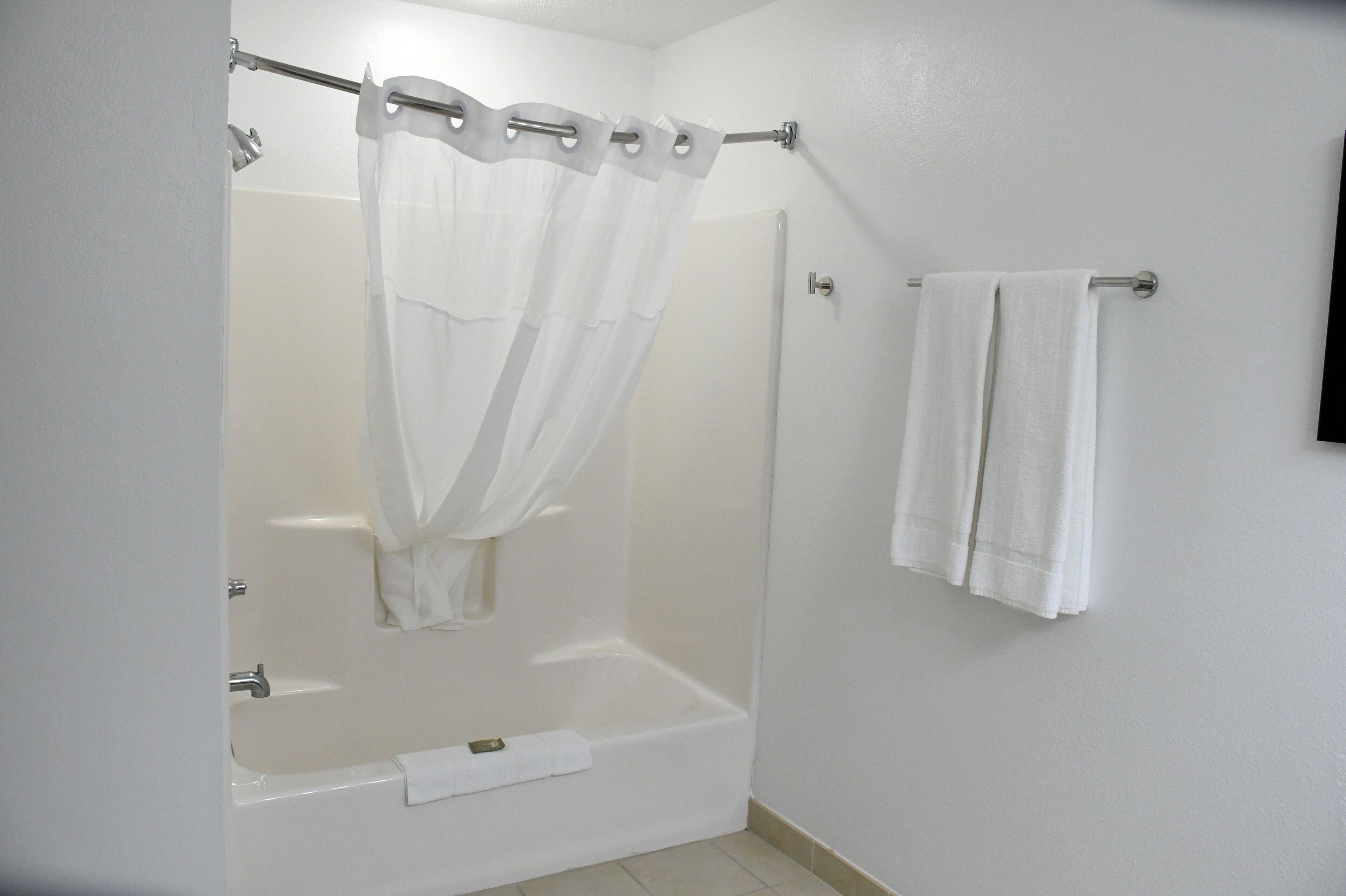Une salle de bain avec un rideau de douche, une baignoire et un porte-serviettes.