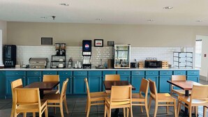 Ein Frühstücksbereich mit einer Theke, Kaffeeautomaten und Sitzgelegenheiten.