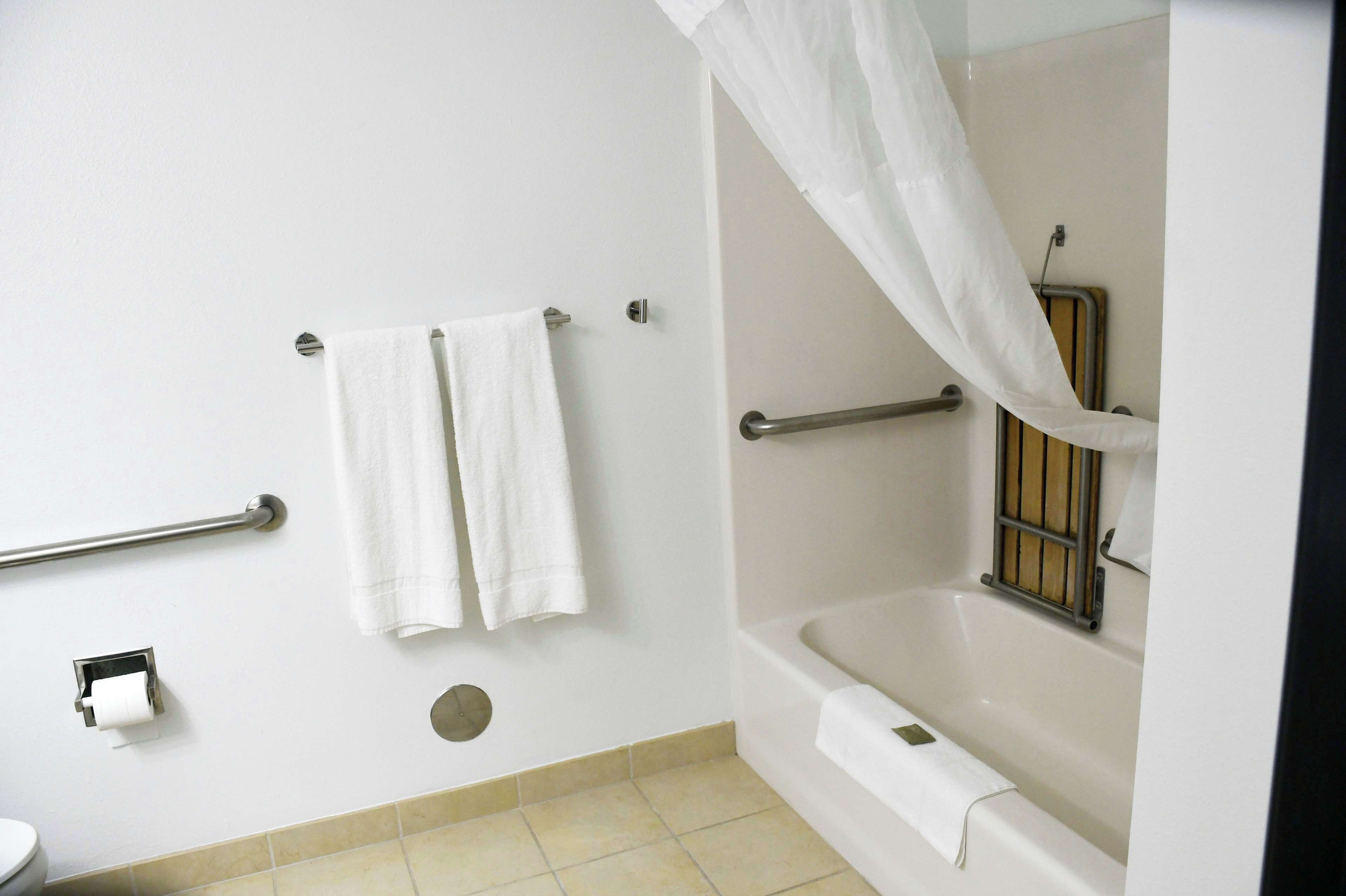 A bathroom with a bathtub, a toilet, and a handrail.