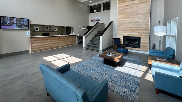 Eine geräumige Lobby mit Rezeption, Treppe, Kamin und Sitzbereichen.