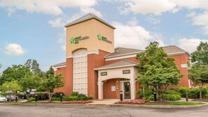Un hotel Stay America con fachada de ladrillo, una torre destacada y la entrada al vestíbulo.