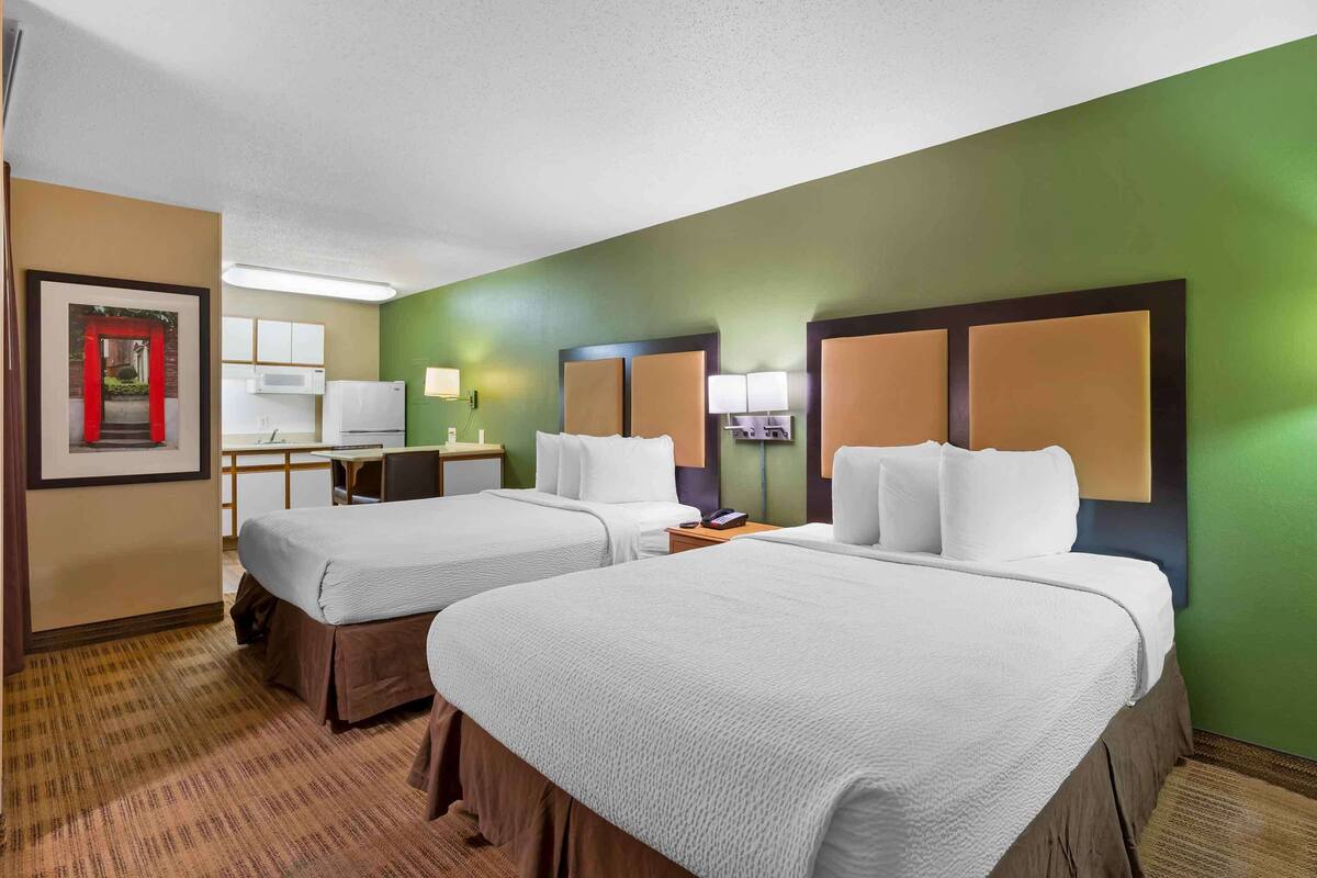 Een hotelkamer met twee bedden, een bureau en een stoel.
