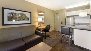 Habitación de hotel con sofá, escritorio, silla y kitchenette.