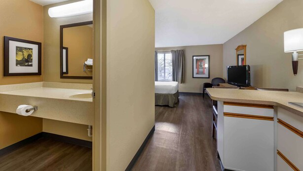 Habitación de hotel con un baño amplio, una cama, un escritorio y un televisor.