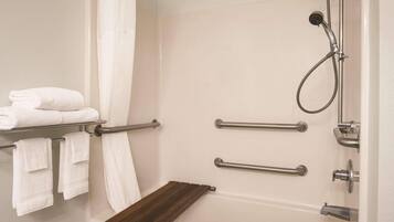 Une salle de bain équipée d’une baignoire, d’une douche et d’un porte-serviettes avec des serviettes pliées.