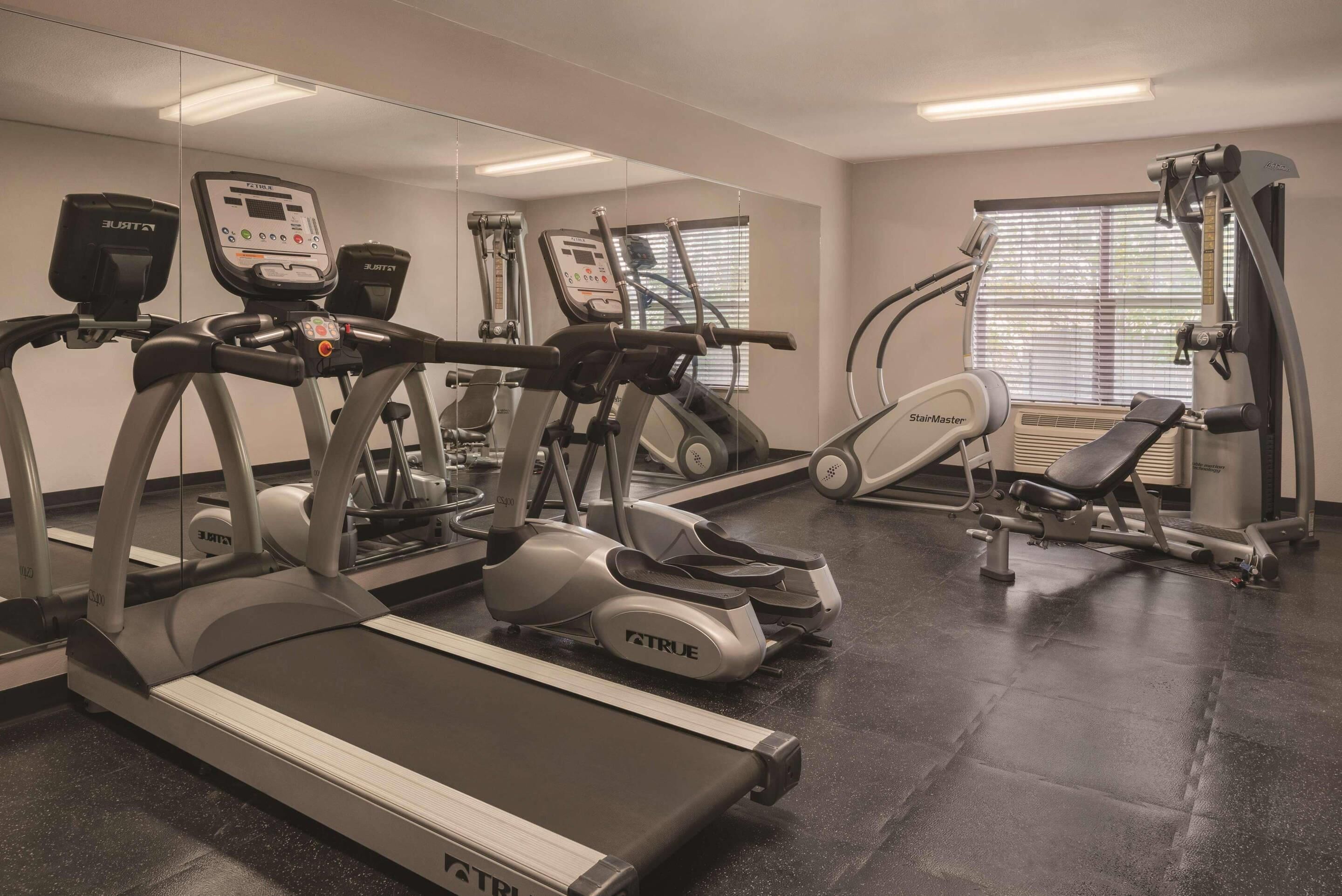 Un gimnasio con cintas de correr, bicicletas estáticas y máquinas de pesas.