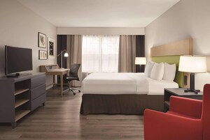 Una habitación de hotel con una cama, un escritorio, un televisor y una silla roja.