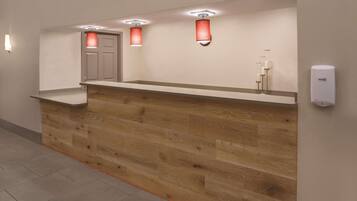 Reception area with a counter and flat surface, featuring a wall-mounted thermostat and tiled floor.