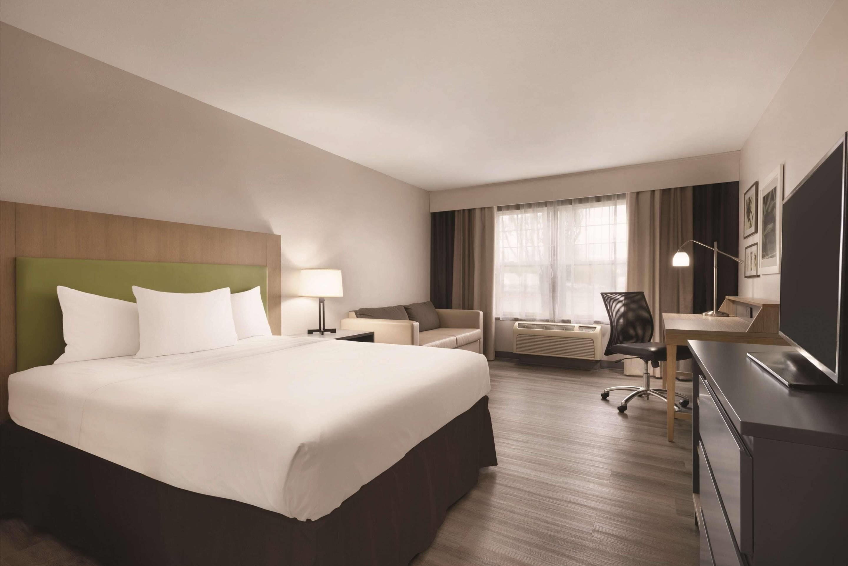 Una habitación de hotel con una cama grande, un escritorio, una silla y un televisor.