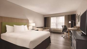 Una habitación de hotel con una cama grande, un escritorio, una silla y un televisor.