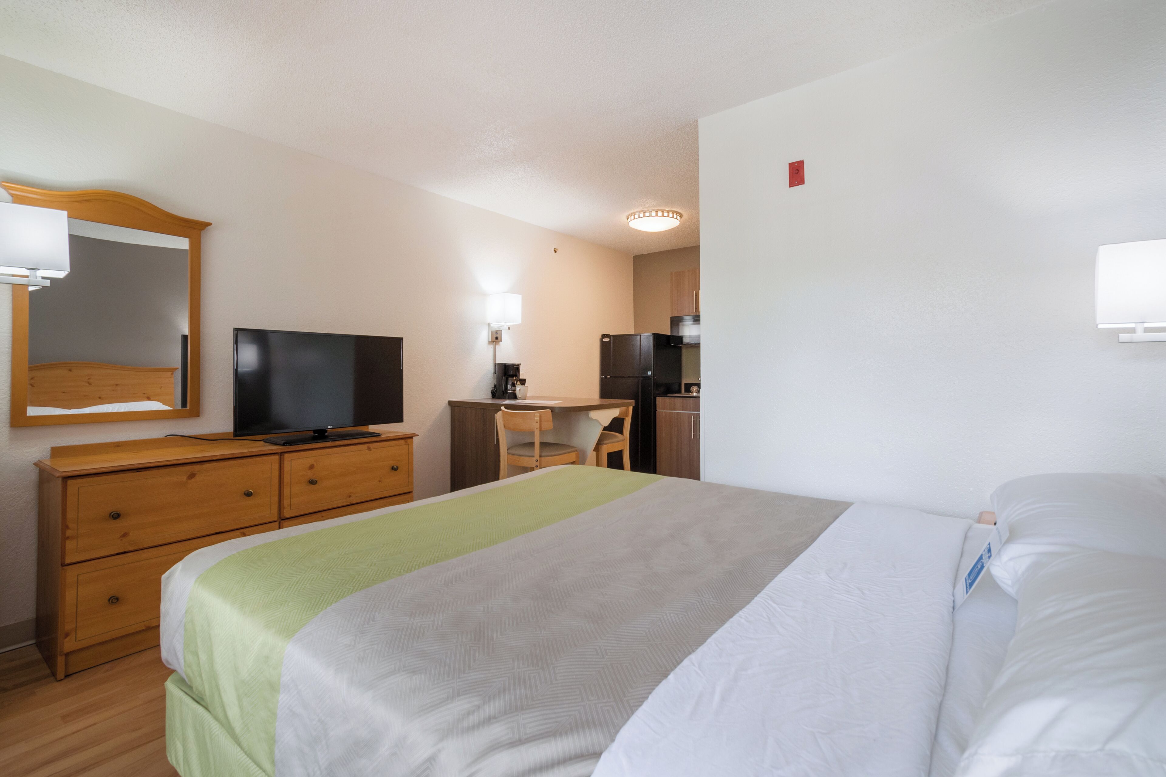 Una habitación de hotel con una cama, un escritorio, una silla, un televisor y un aparador.