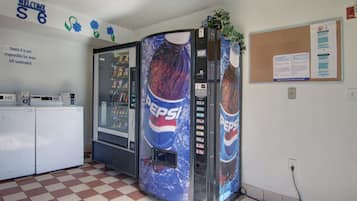 A room with a vending machine, a refrigerator, and a bulletin board.