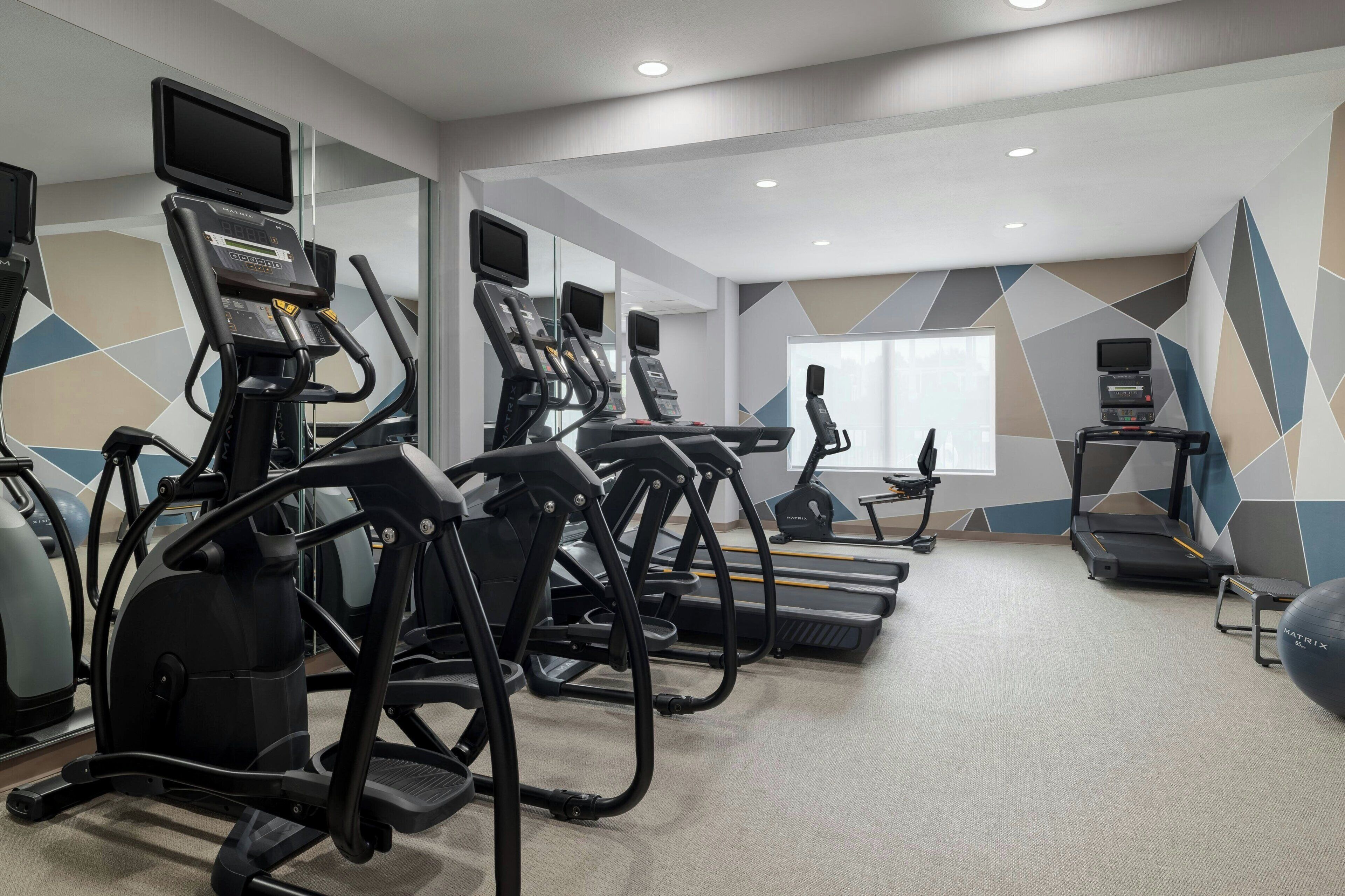 Un gimnasio con cintas de correr, elípticas y pelotas de ejercicios.
