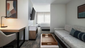 A hotel room with a desk, a sofa, a bed, a TV, and artwork on the walls. - SpringHill Suites Dallas Arlington North (Arlington)