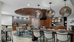 A modern dining area with a long table, multiple chairs, and hexagonal pendant lights. - SpringHill Suites Dallas Arlington North (Arlington)