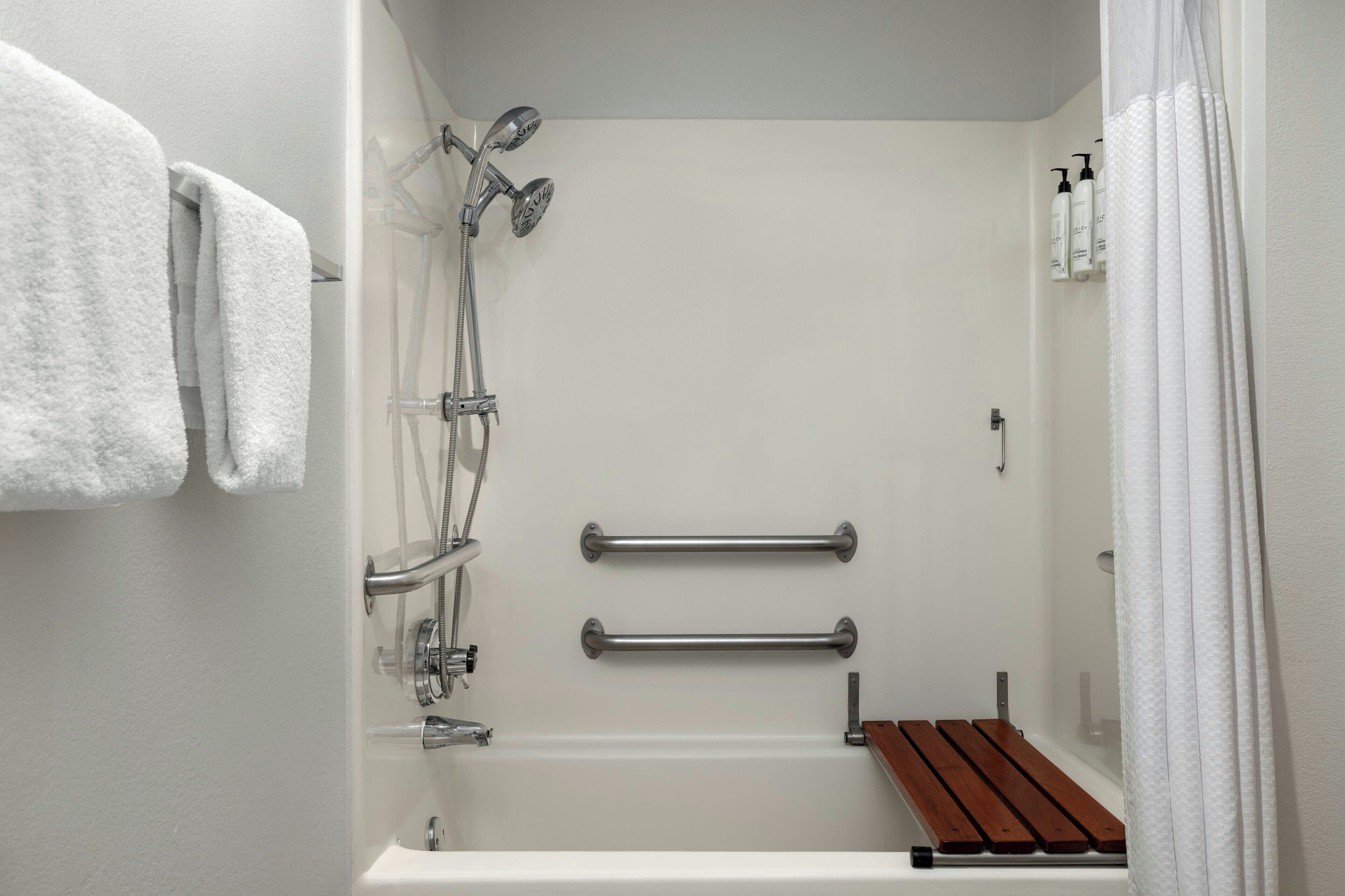 A bathroom with a bathtub, shower, and two towel racks.