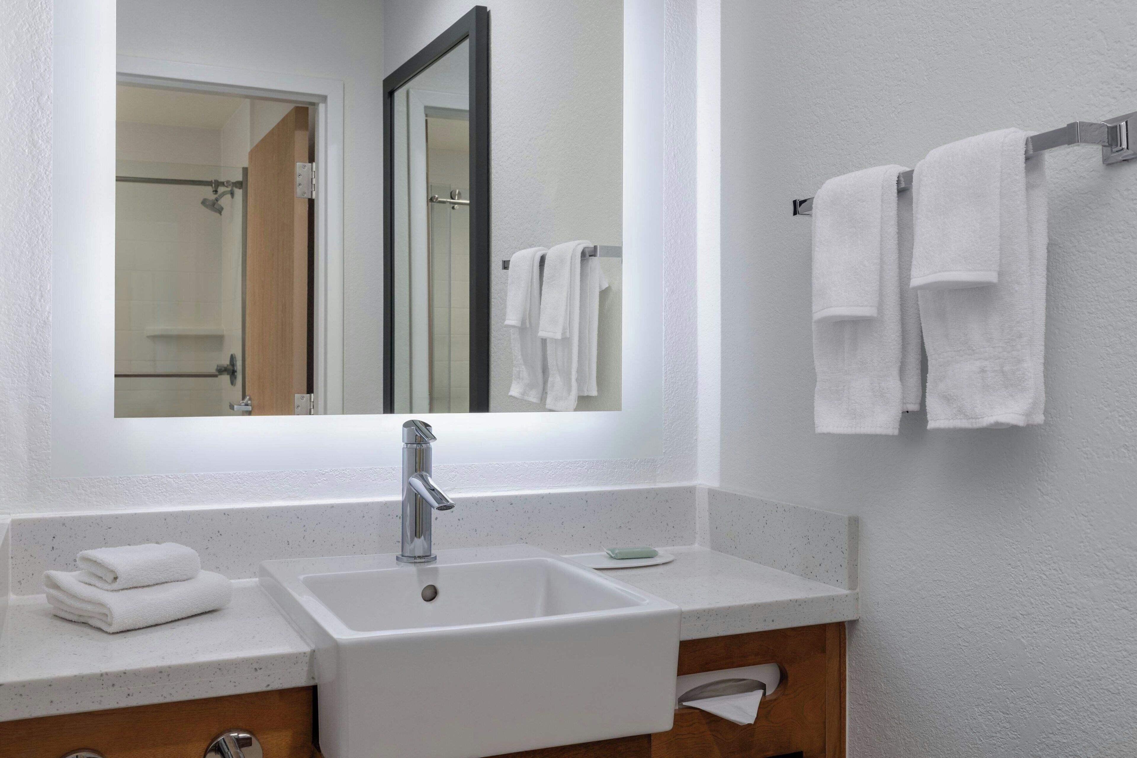 A bathroom with a white sink, a mirror, and a towel rack.