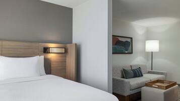 Una habitación de hotel con una cama, un sofá, una lámpara y un cuadro en la pared.