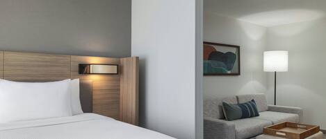 A hotel room with a bed, a sofa, a lamp, and a painting on the wall.